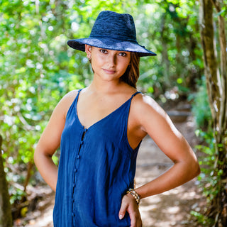 Woman walking along a sunny trail, accessorized with the Wallaroo Victoria Fedora Sun Hat, perfect for summer coastal getaways, 'Mixed Navy'