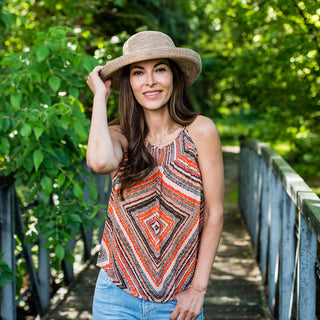 Woman admiring a luxurious garden, wearing the Wallaroo Women’s Victoria Sun Hat, ideal for stylish sun coverage on warm summer afternoons, 'Mixed Camel'