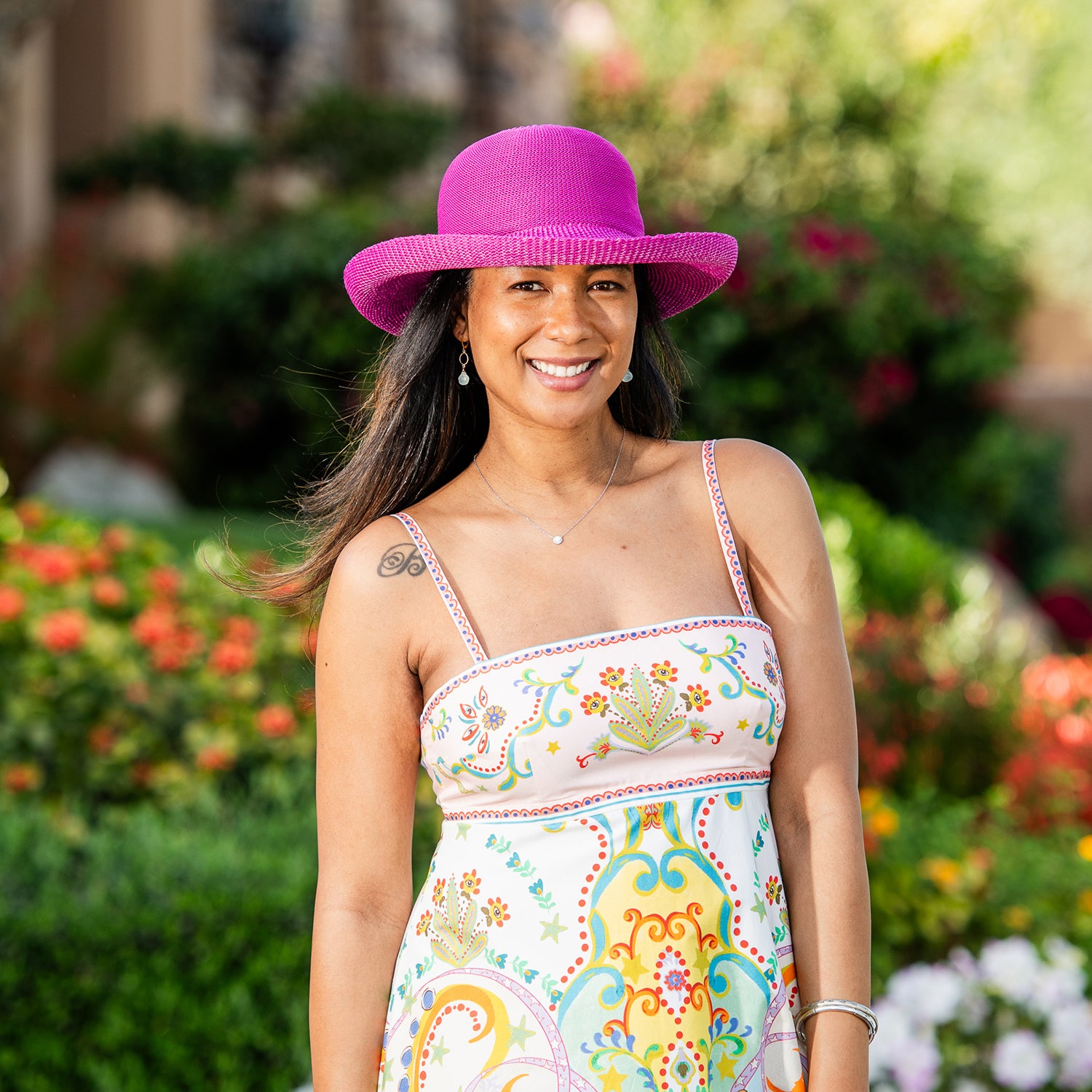 Woman wearing a colorful dress and Victoria sun hat in a garden setting, Raspberry