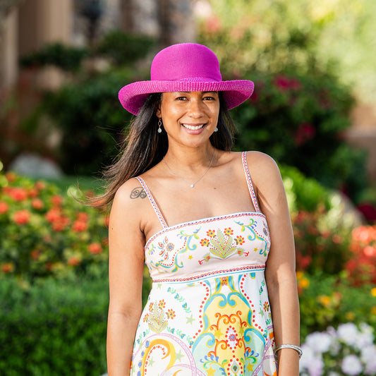 Woman wearing a colorful dress and Victoria sun hat in a garden setting, Raspberry