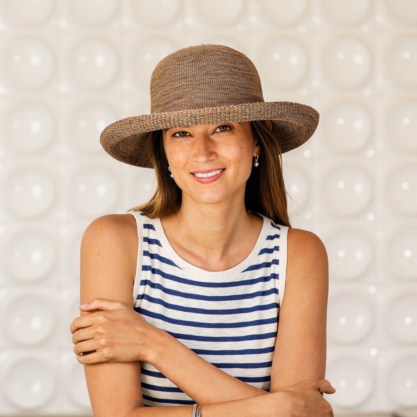 Woman wearing a Victoria hat and striped tank top against a textured background, Suede
