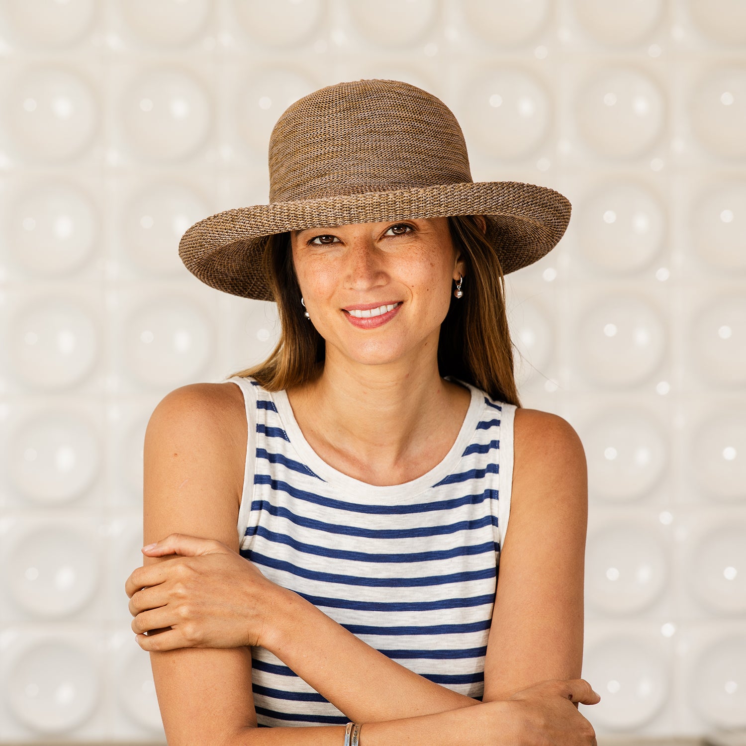 Woman wearing a Victoria hat and striped tank top against a textured background, Suede