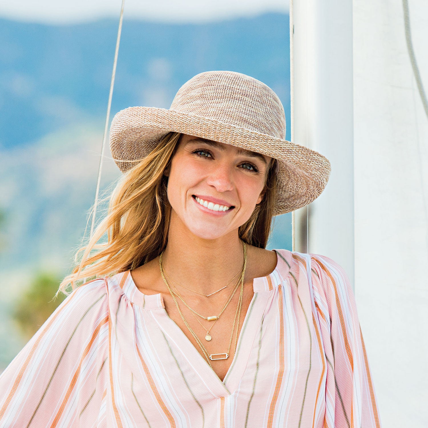 Woman at the marina shaded by the Wallaroo Women’s Victoria Sun Hat, designed for hot days and fashionable summer outings, Mixed Camel