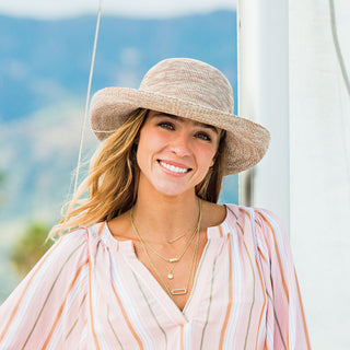 Woman at the marina shaded by the Wallaroo Women’s Victoria Sun Hat, designed for hot days and fashionable summer outings, 'Mixed Camel'