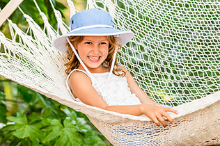 Girl in Junior Explorer hat lying in a hammock