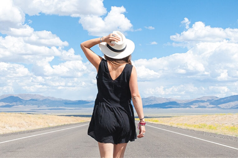 Woman walking in the middle of the road wearing a Wallaroo sun hat