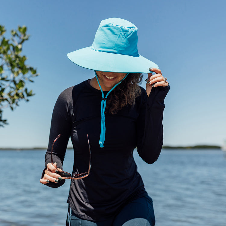 Woman Wearing a packable Waterproof Turquoise Sun Hat for the beach with Chinstrap 