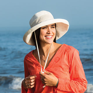 Woman Wearing a Packable Wide Brim Seaside UPF Sun Hat with Chinstrap in Natural from Wallaroo